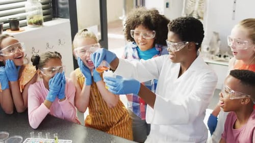 Diverse female teacher and happy schoolchildren having science class in school lab