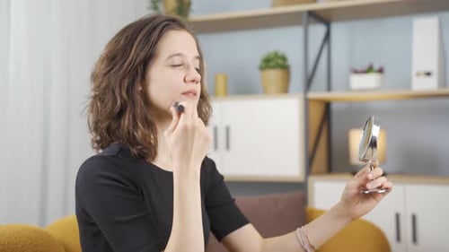 Woman Applies Makeup with Brush Looking in Mirror