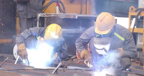 Welders Working At Construction Site Using Welding Mask To Protect Their Eyes.