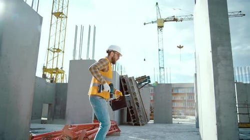 Construction Worker Carrying Drill at Building Site