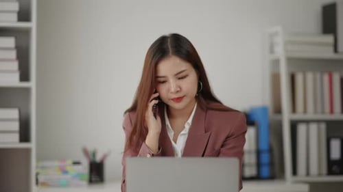 Young Woman Talking on Phone at Her Desk