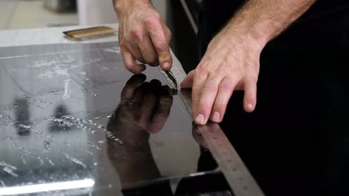 Tradesman cuts film with cutter and ruler