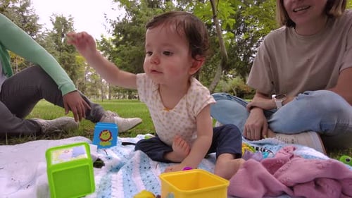 Cute little latin baby girl playing with her toys on the ground at the park