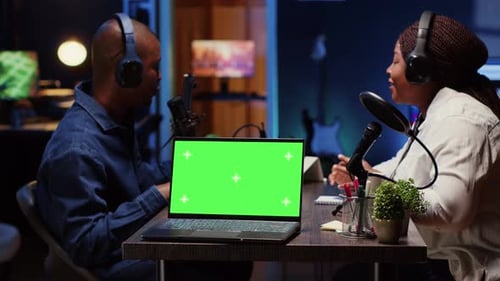 Green Screen Laptop Next to Man on Podcast Discussing with Guest During Marathon Stream