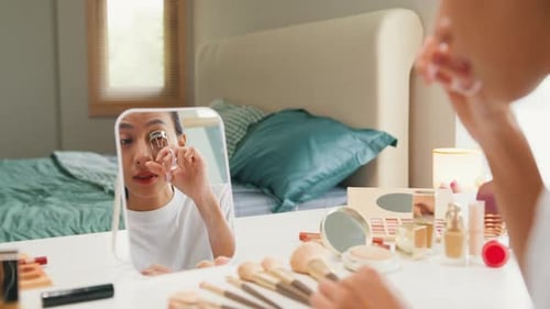 Woman Styles Eyelashes with Curler in Home Setting