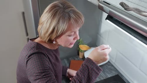 Overhead View of Woman Tasting Freshly Cooked Food in Bright Kitchen