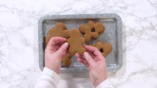 Hands Place Gingerbread Men Cookies on Tray