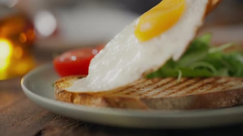 Fried Egg Being Placed on Bread
