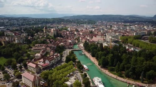 River Le Thiou running through the Annecy city centre. Ferries are moored up for tourist to visit.