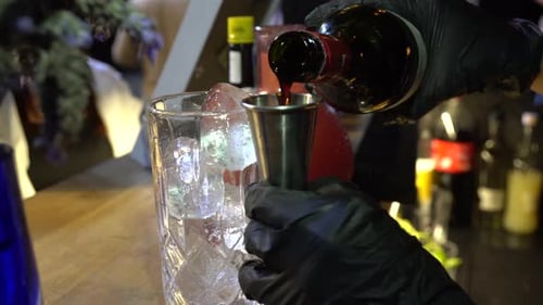 Bartender hands in black gloves making cocktail