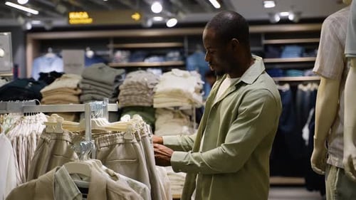 African American Customer Choosing Beige Pants in Clothing Store
