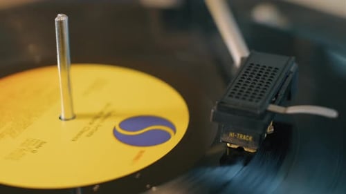 Close up of a vintage lp vinyl record spinning on a turntable. The yellow label is prominent and the