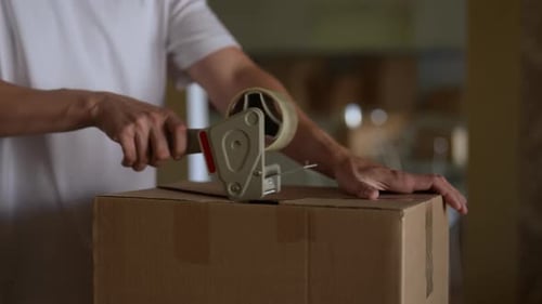 Man Sealing a Cardboard Box with Tape