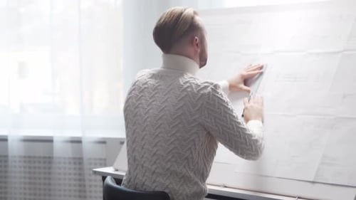 Concentrated Architect Works in Loft Using Drawing Board Workplace of Young Engineer in Modern
