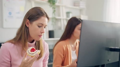 Group of businesswoman eating doughnut while working in the office.