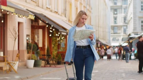 Woman Tourist With Luggage Looks at Map on Street