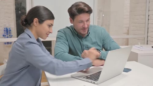 Coworkers Collaborate on Laptop Project in Bright Office