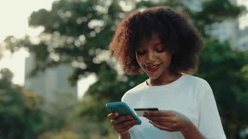Portrait of African American Lady Paying with Credit Card on Internet in Park