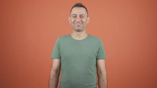 Smiling Man Standing in Front of Orange Background