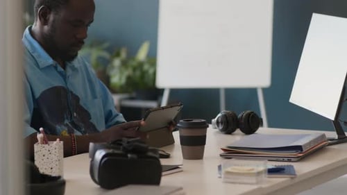 Jeune spécialiste noir travaillant sur une tablette numérique