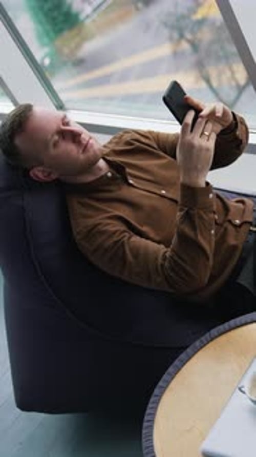 Man Relaxes with Phone in Modern Workplace