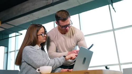Man and Woman Collaborate on Laptop in Office