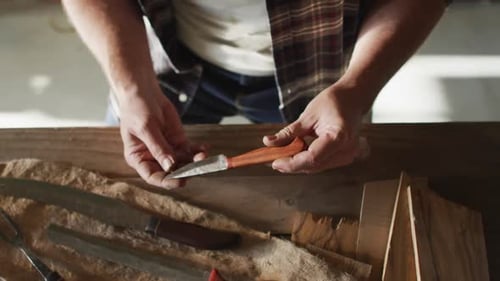 Mittelteil eines kaukasischen männlichen Messermachers in der Werkstatt, Messer in der Hand