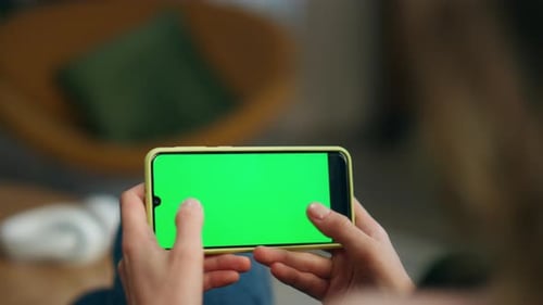 Woman Holds Phone with Green Screen in Home