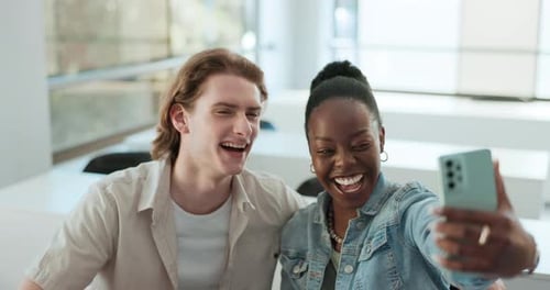 Two Smiling Young Adults Looking at Phone Together