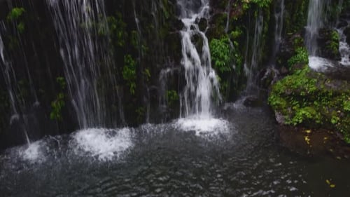 Drone footage of Banyu Wana Amertha Waterfall in Bali. Lush tropical jungle, cascading water, and pe