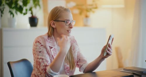 Woman Having Video Call On Smart Phone In Office Talking With Client