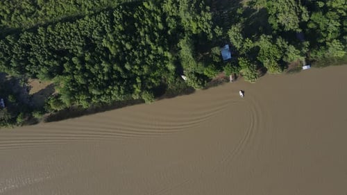 Drone footage of small boat on brown water amazon river arriving home and making soft waves. 4K aeri