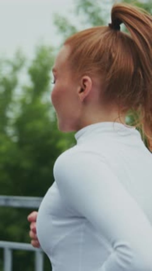 A Young Woman in Athletic Wear Jogging Outdoors Amidst Lush Greenery Capturing the Energy and Joy of