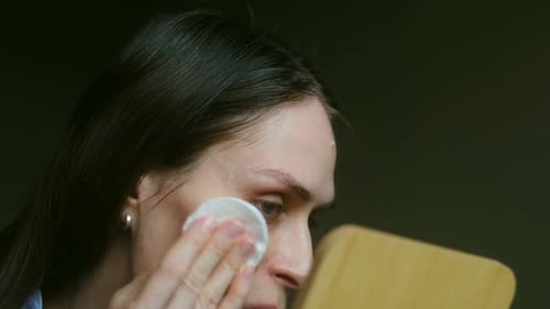 Woman Cleansing Face Skin with Cotton Pad
