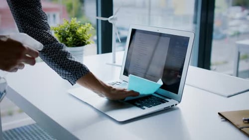 Unrecognizable Woman Back at Work in Office After Lockdown, Disinfecting Laptop