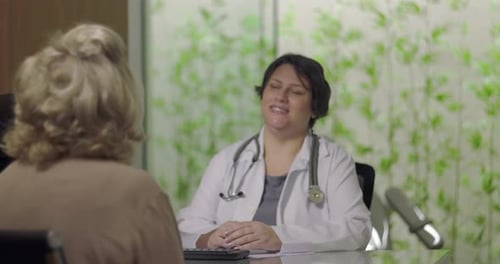 Female doctor attentively listening to senior female patient during medical consultation in clinic