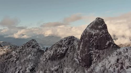 Dramatic Mountain Terrain Snowy Mountain Peak Cloudy Winter Sunset Aerial BC Canada