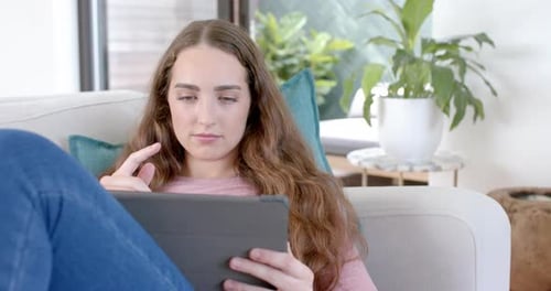 Woman Uses Tablet, Relaxing on Couch at Home
