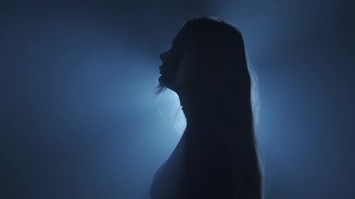 Silhouette in Lighting Concept Female Model Against Bright Strobing Light on Black Smoky Background