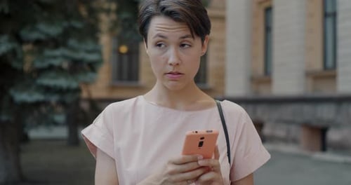 Portrait of Young Lady Using Smartphone Texting Standing in City Street on Summer Day