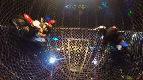 deux pilotes de motocross présentent un spectacle acrobatique dans une cage ronde en acier