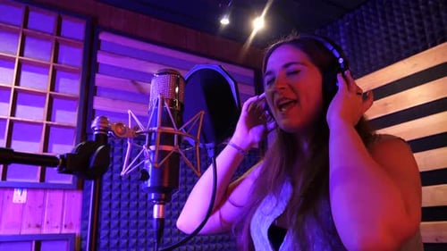 Beautiful woman singing to the microphone in a studio. Slow motion.