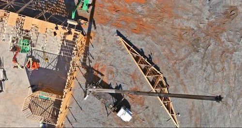Mit Hilfe eines Krans werden Dachbinder aus Holz an einem neuen Wohngebäude installiert