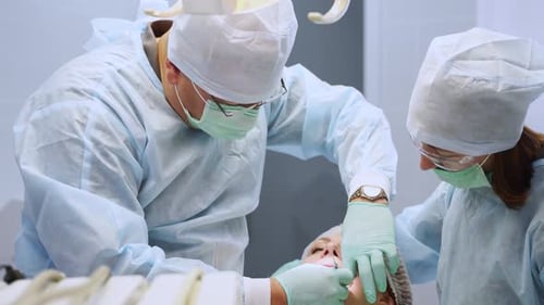 Installation of Dental Implants in Modern Dental Clinic Oral Surgeon and Nurse During Operation in