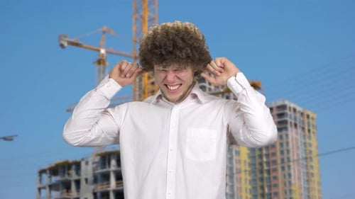 Young Man in White Shirt Close His Ears with Both Fingers Outdoors