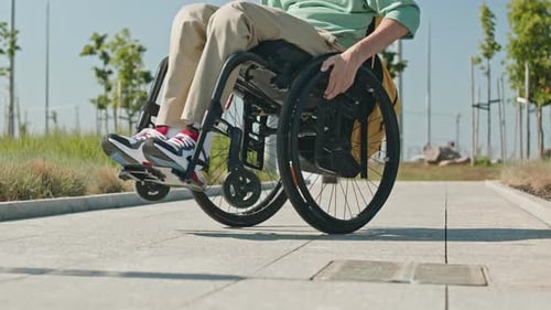 Young Adult Using Wheelchair on City Path