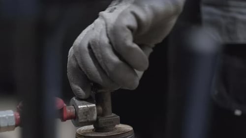 Gloved Hand Turns a Valve on Machinery