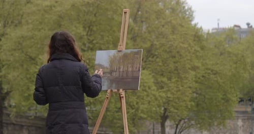 Frau malt ein Bild in der Nähe der Seine Kreative Künstlerin malt ein Bild mit einem Pinsel