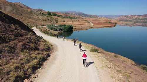 Aerial View Of Group Of Friends Cycling On The Shore Of The Reservoir