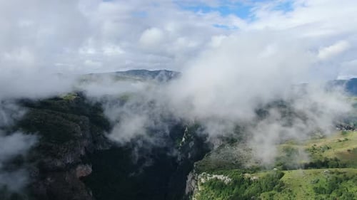 Dramatic aerial view of a mountain valley filled with low hanging clouds partially obscuring the